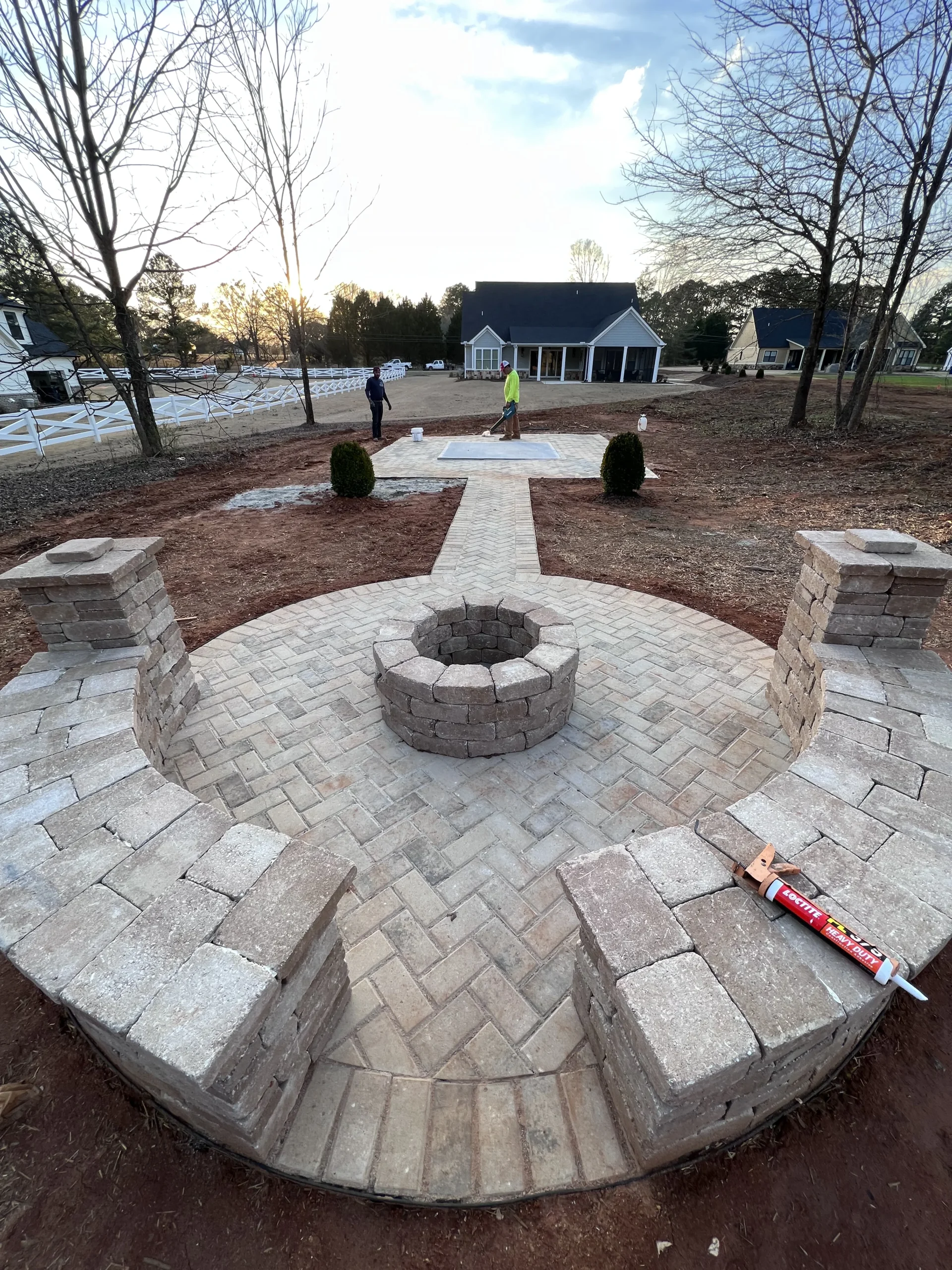 Outdoor paver patio installation with circular stone fire pit feature