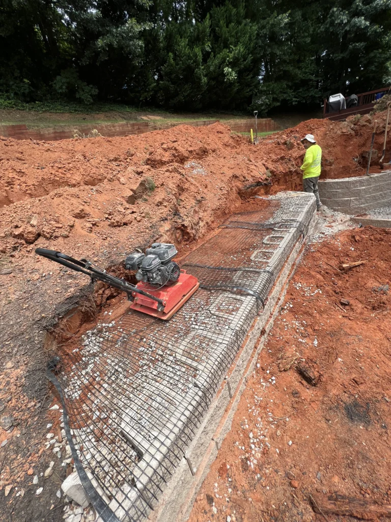 Masonry contractor installing segmental retaining wall with geogrid reinforcement in Metro Atlanta