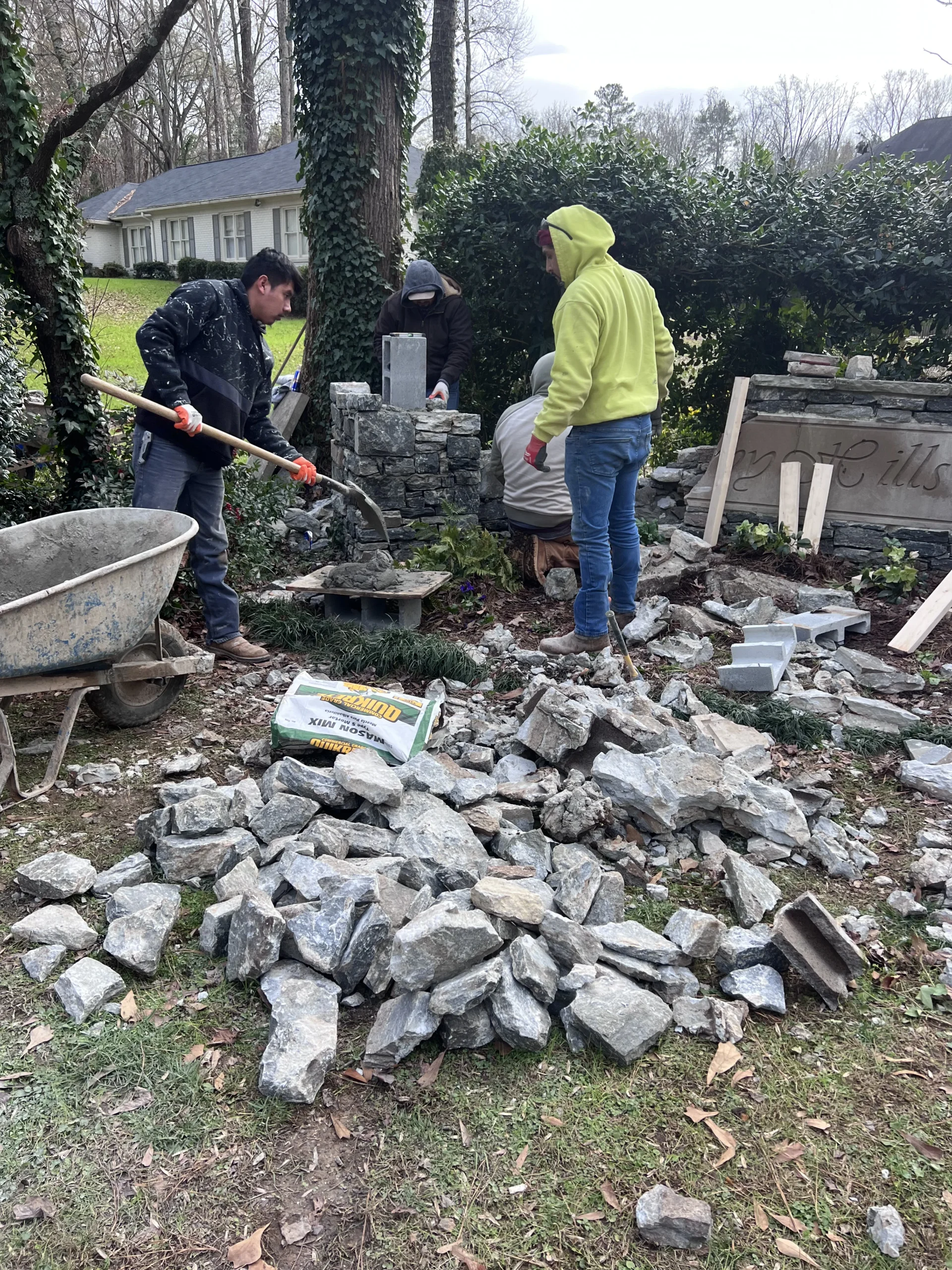 Masonry crew installing stone column and entry sign for residential community in Metro Atlanta